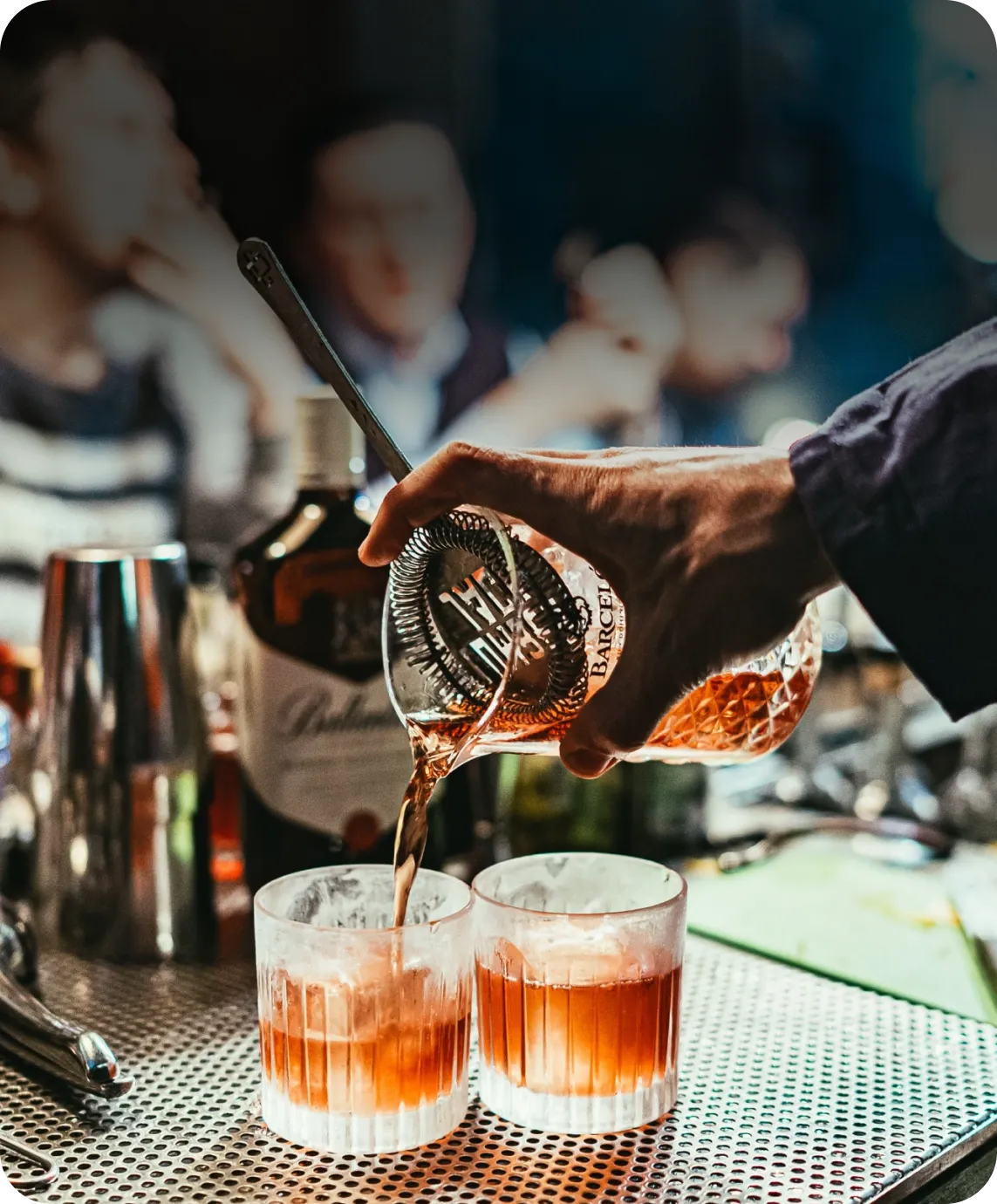 A bartender expertly pours a drink into two glasses, creating a delightful concoction for patrons to enjoy.