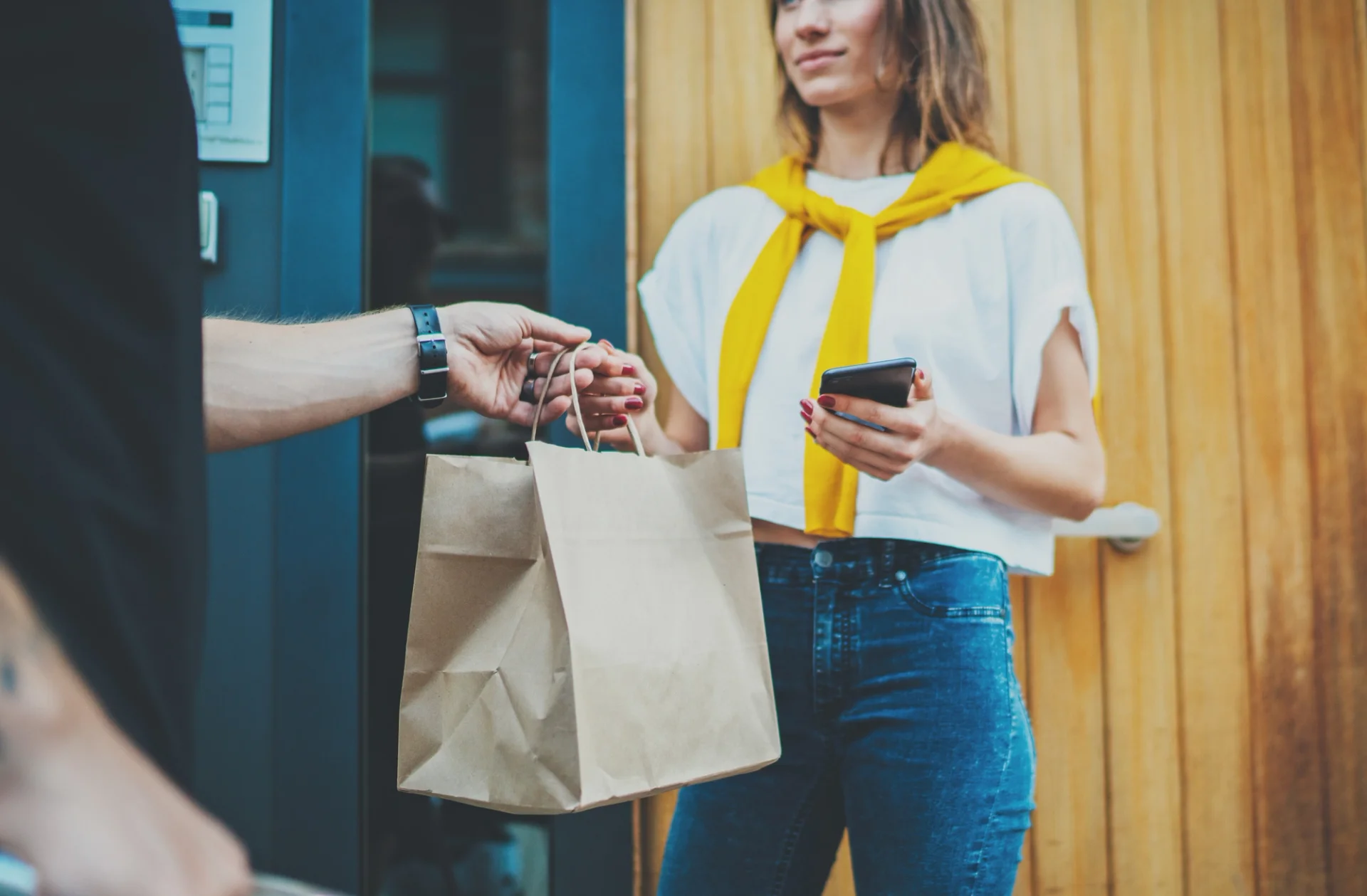 A man delivering a paper bag to a woman, representing a food delivery service.