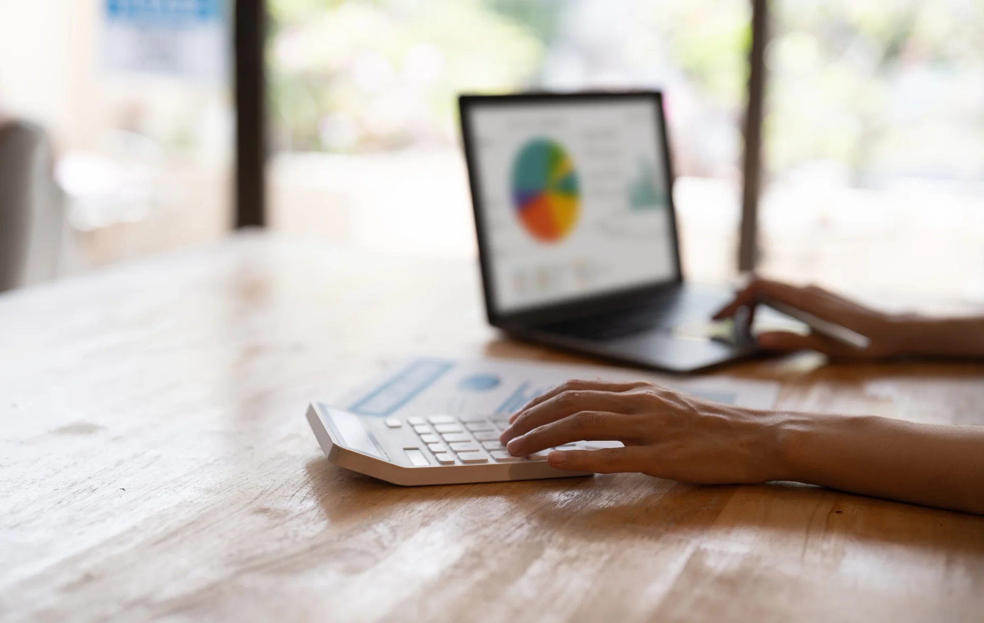 Image of someone typing on a laptop with a calculator, emphasizing the importance of cost control.