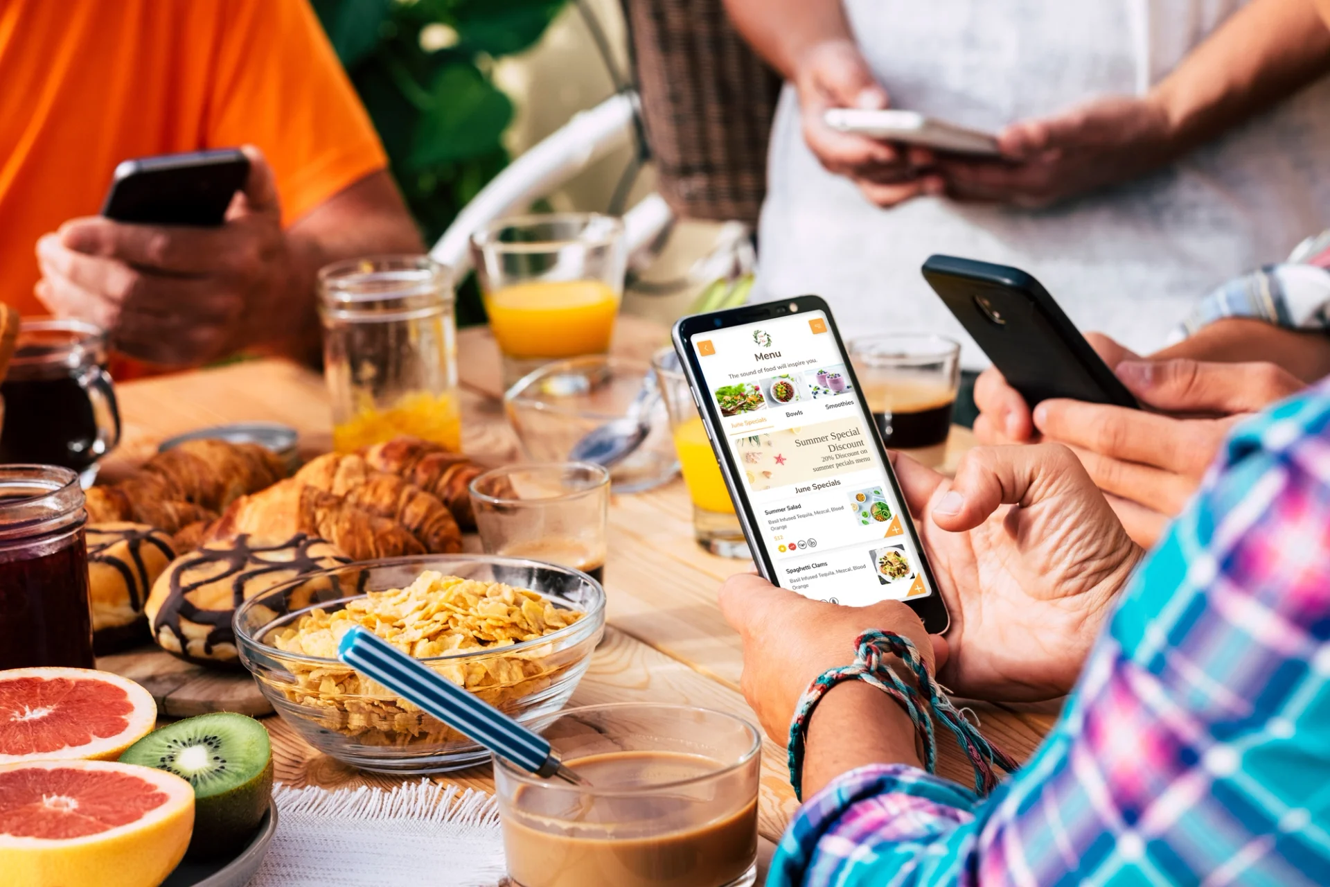 People at a table in a restaurant, engrossed in their phones while enjoying their meal.