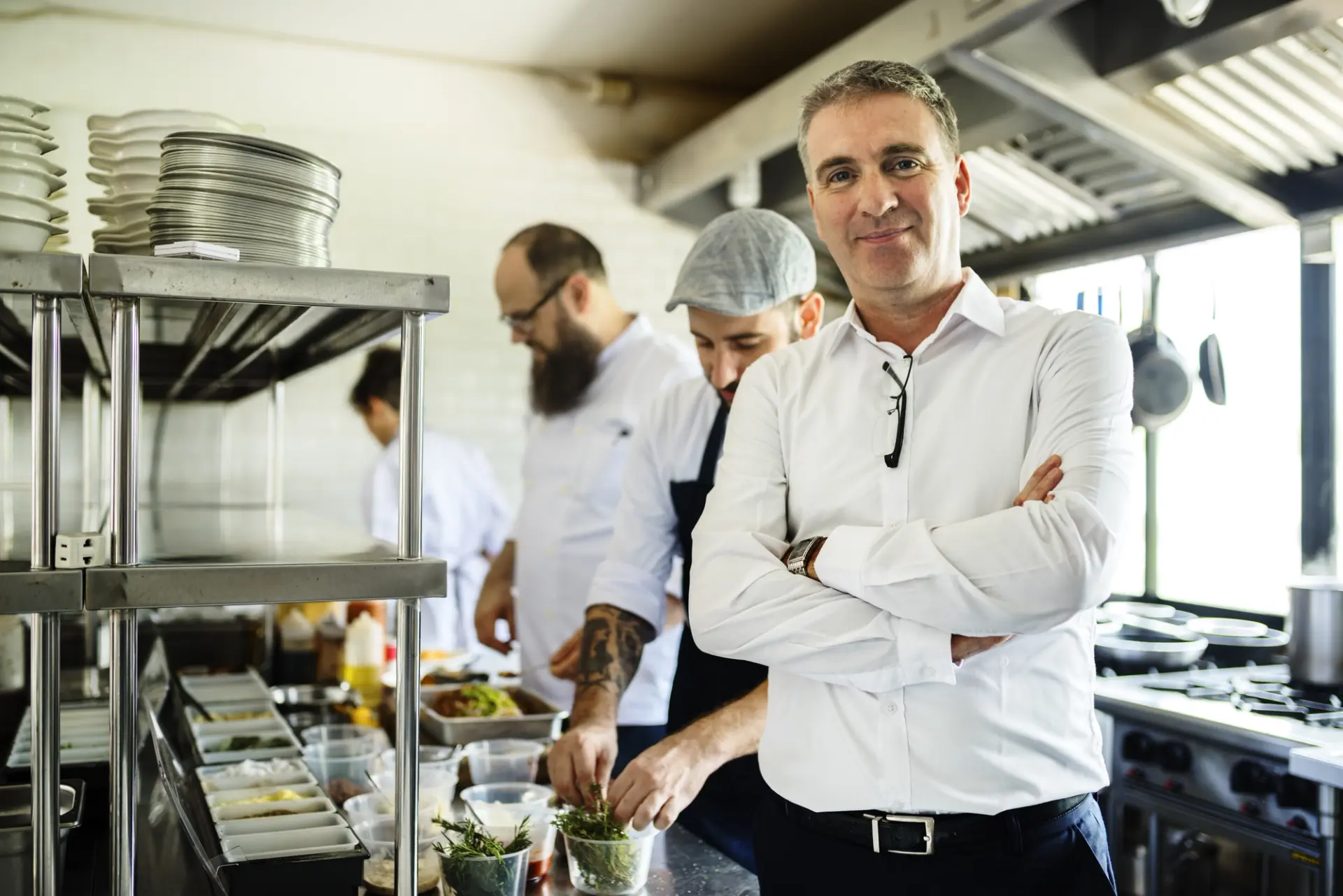 A group of chefs, including a restaurant manager, standing in a busy kitchen, preparing meals.
