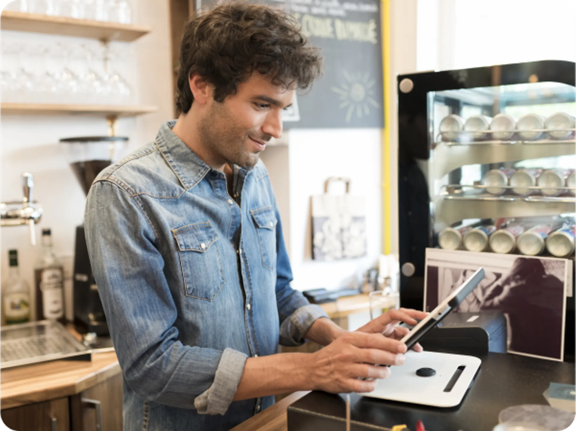 A man in a coffee shop using a tablet to seamlessly send orders from FineDine to Revel.