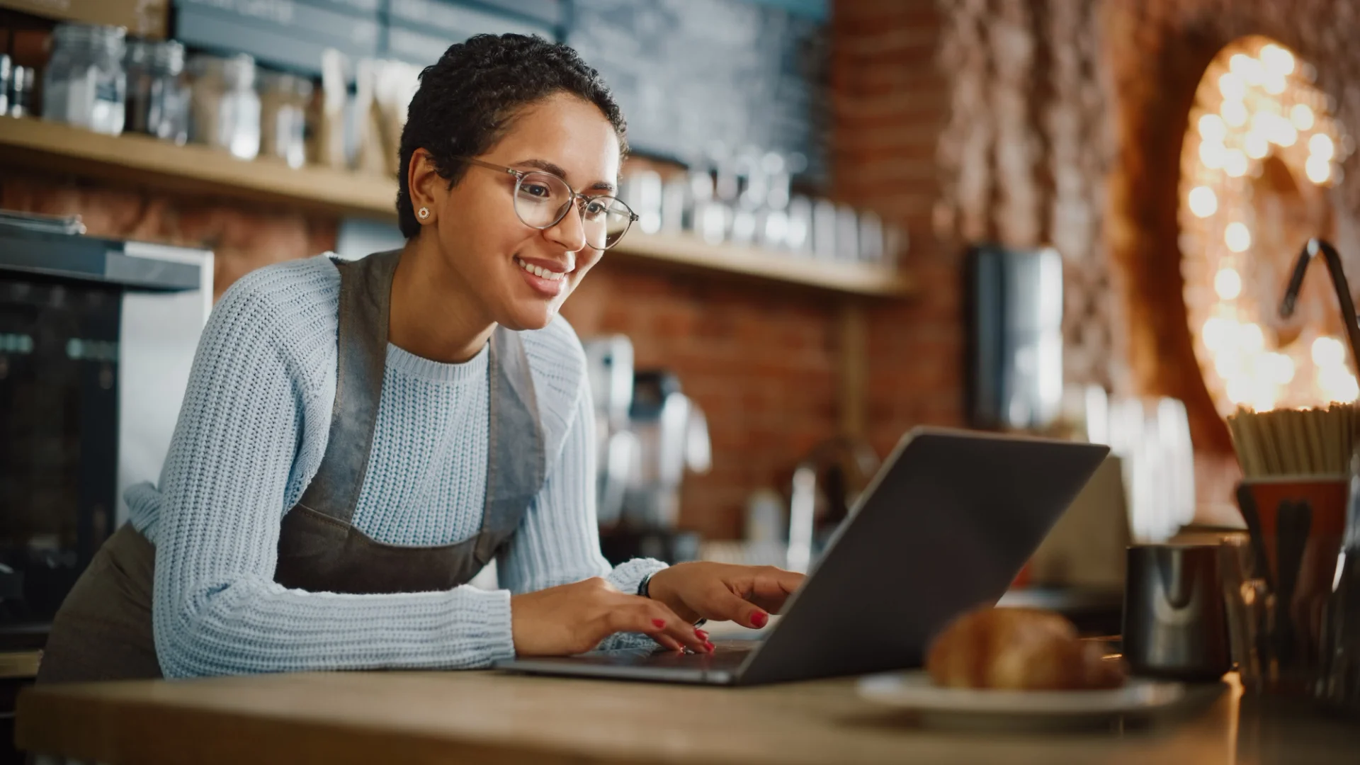 A focused woman works on her laptop and managing online orders.