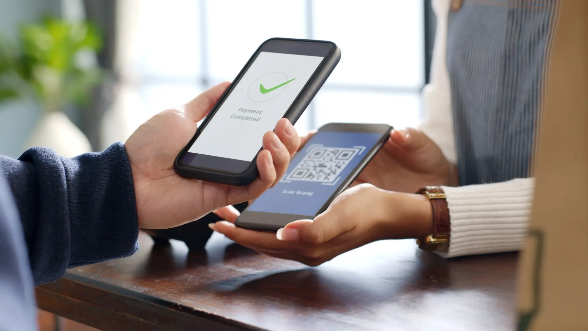هاتفان متقابلان: أحدهما يعرض رمز QR والآخر تأكيد إتمام الدفع