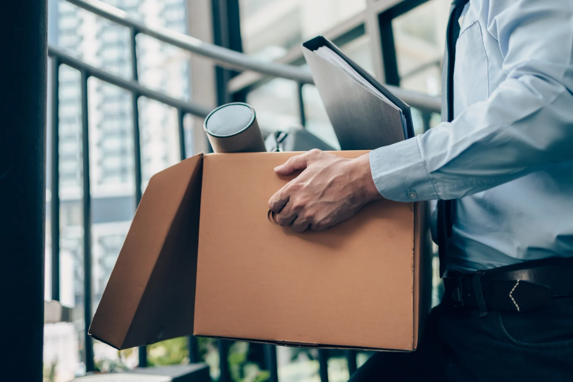 A man carrying a box with a laptop and papers,