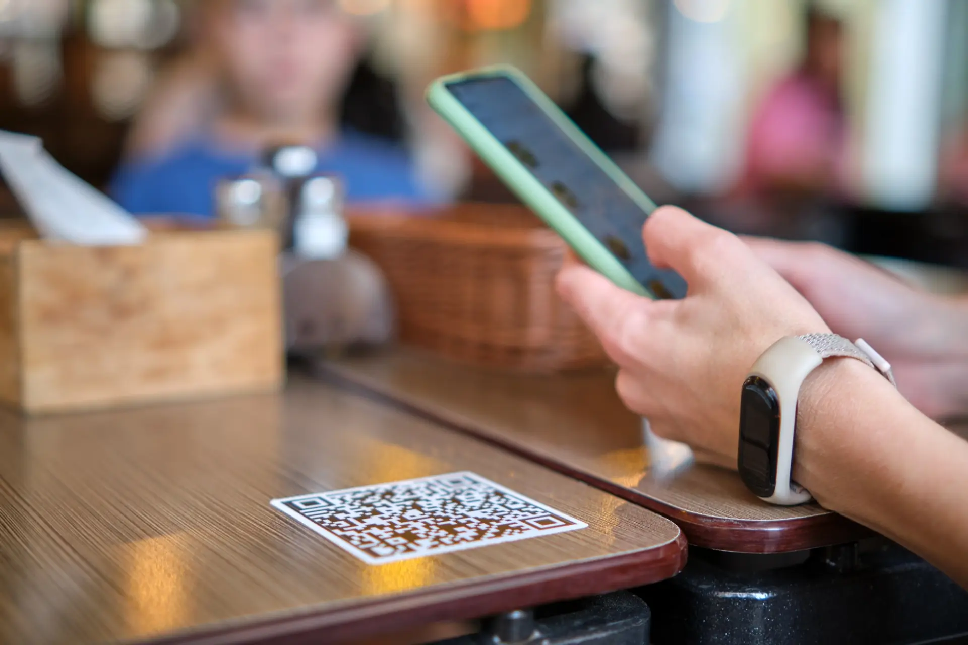 ملصق رمز QR على طاولة مطعم وضيف يحمل هاتفه فوقه