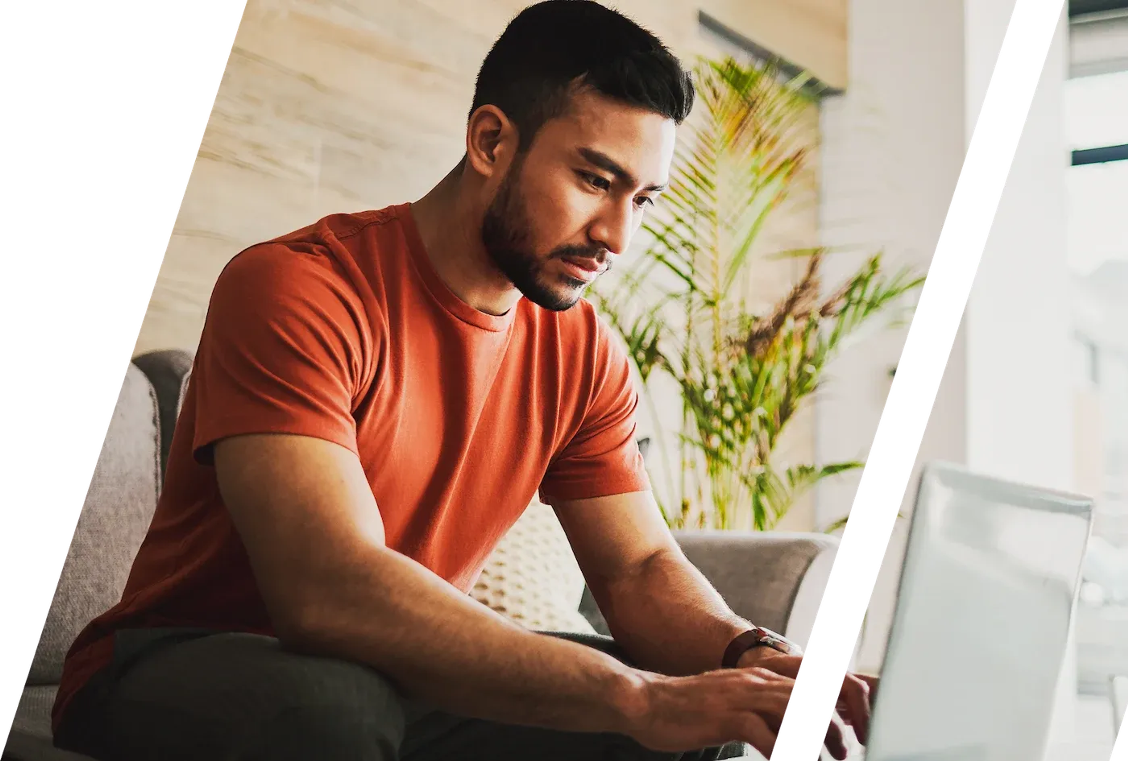 a man in an orange t-shirt works on his laptop