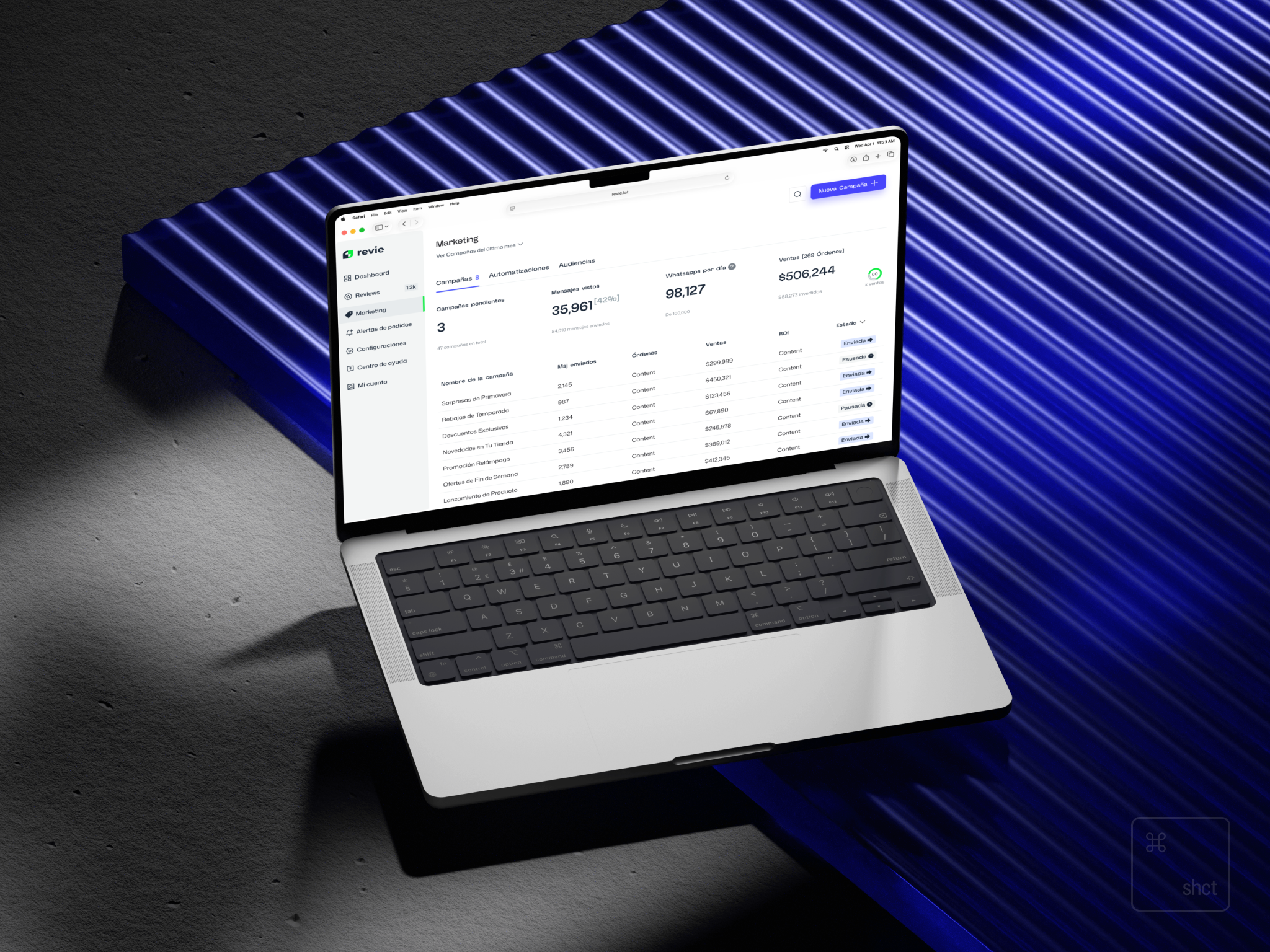 Angled laptop mockup displaying the redesigned Revie marketing dashboard with campaign metrics and status table on a dark blue surface.