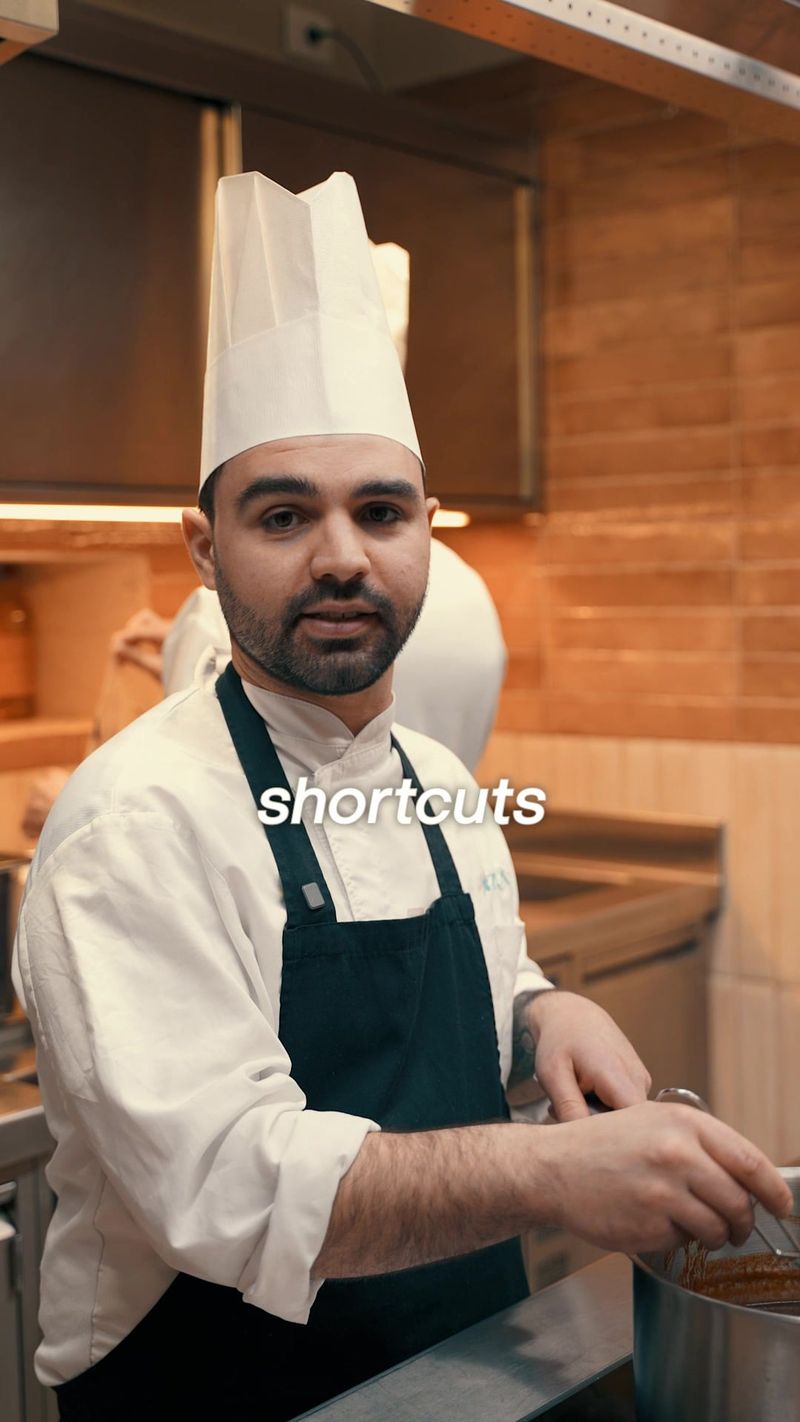 Uno chef con il cappello bianco lavora davanti ai fornelli