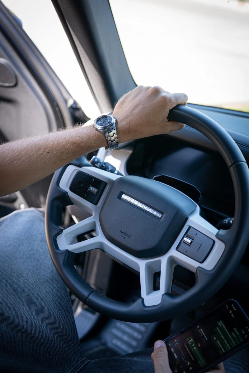 Le mani di una persona sul volante di un'auto sportiva, viste dal sedile accanto