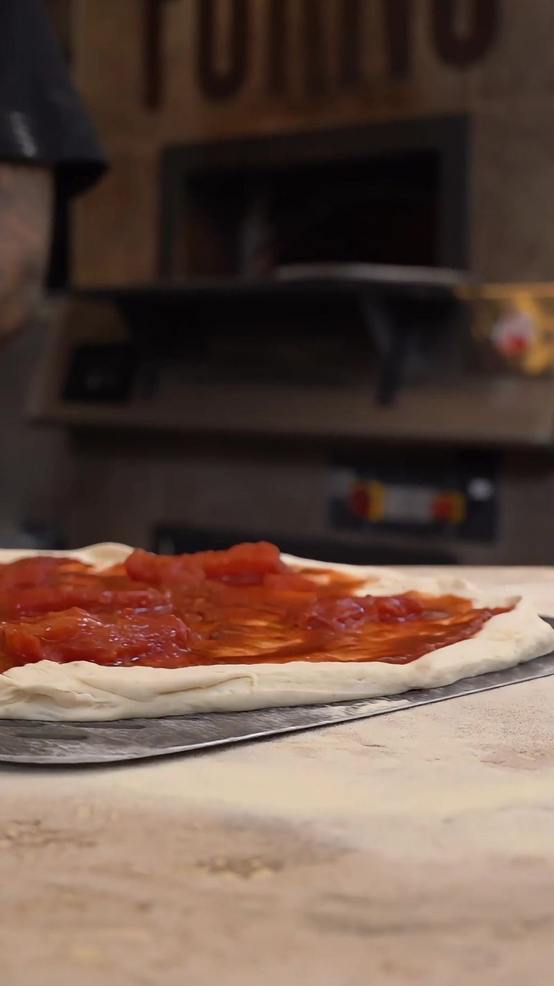 Una pizza su una pala di legno davanti alla bocca di un forno a legna