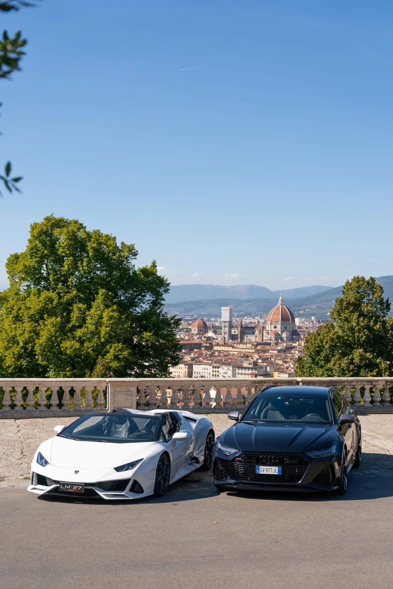 Due auto sportive parcheggiate su un piazzale panoramico con Firenze sullo sfondo