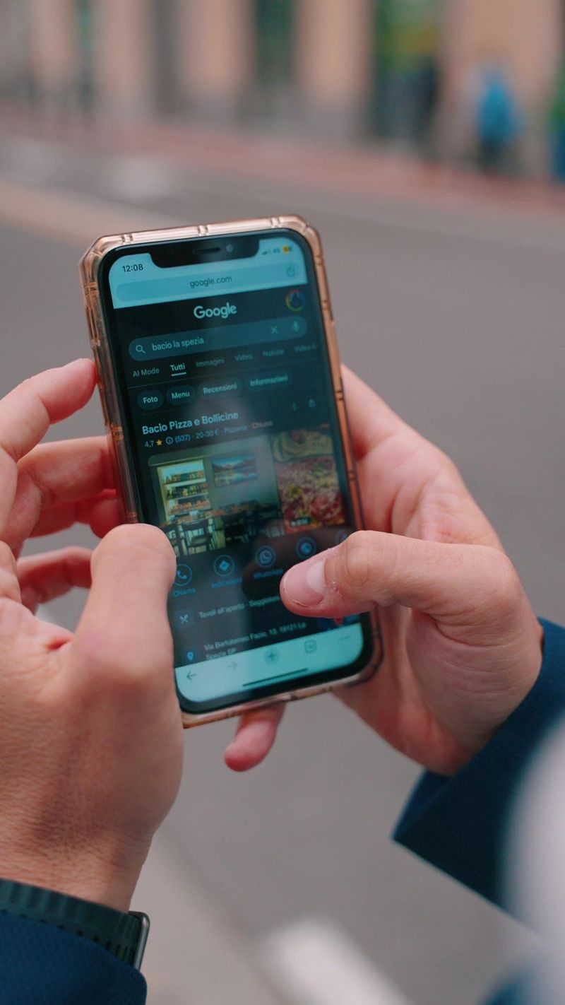 Due mani tengono un telefono che mostra la scheda Google di un'attivita'