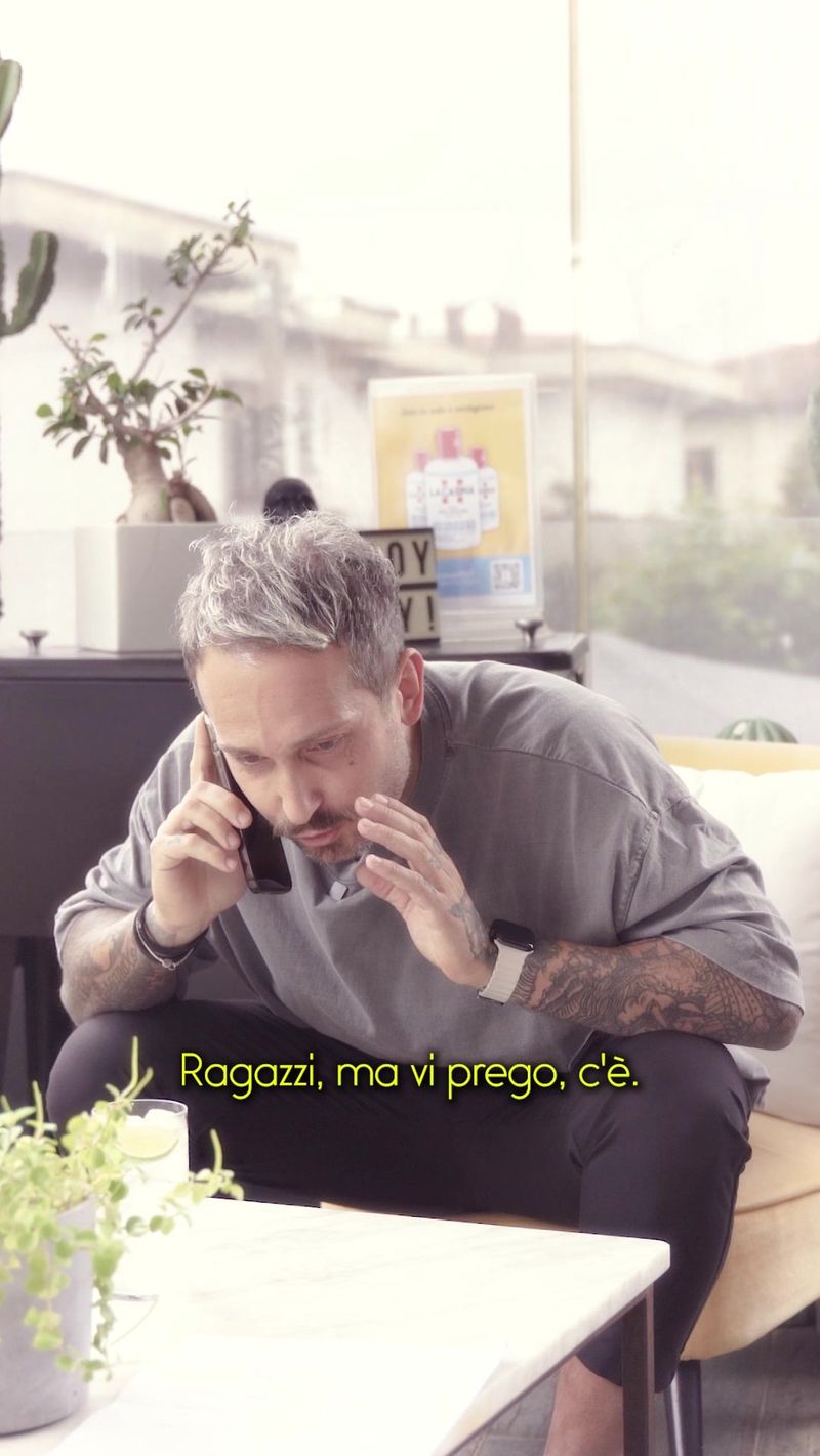 Un uomo seduto a un tavolo all'aperto parla al telefono