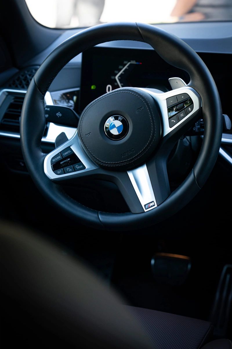 L'interno scuro di un'auto, inquadrato sul volante e sulla plancia