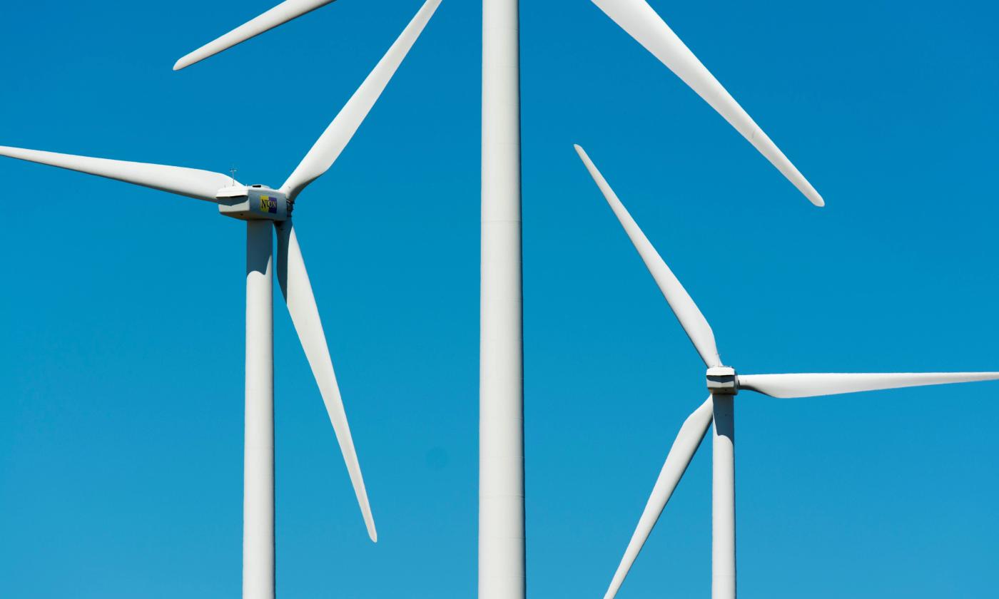The main image for this comundo blog post about ESG managers shows the tops of three wind turbines against a blue blue sky. The turbines are slender and white, making for a nice contrast against the blue sky