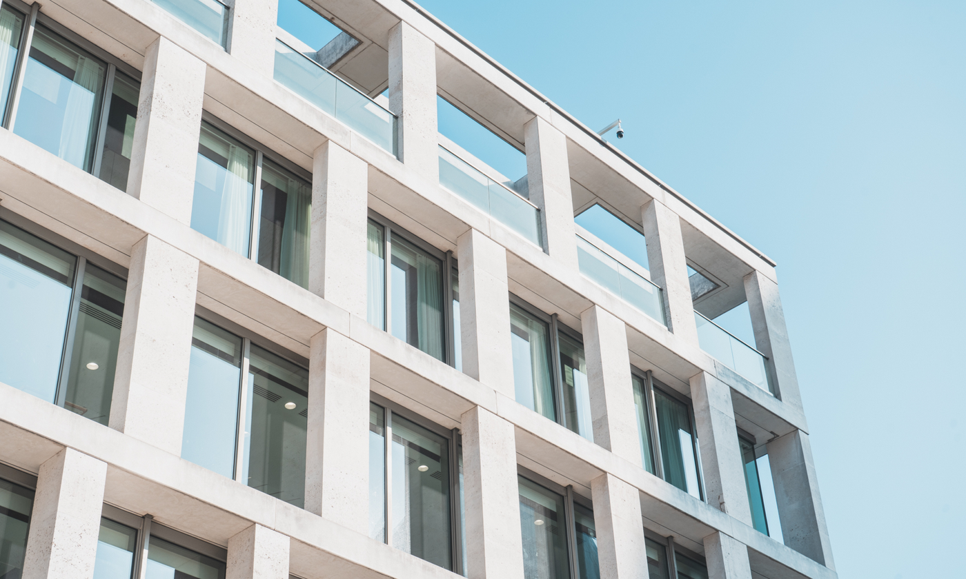 The main image for this comundo blog post about the SBTi building guidelines shows a close-up photo of the corner of a building against a blue sky. The building facade is white and the windows reflect the blue sky. It's a pleasing image