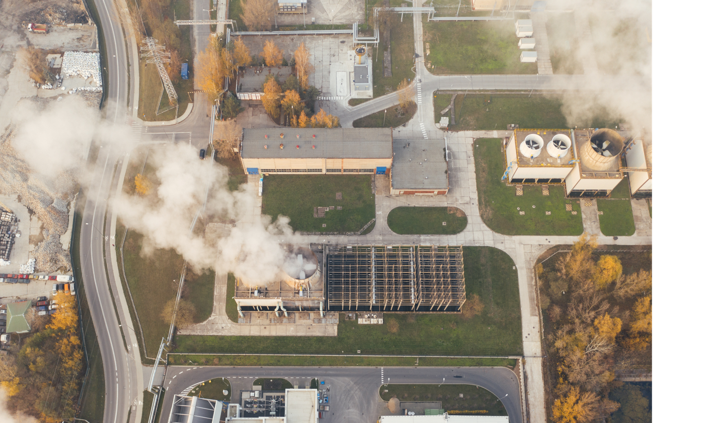 An aerial view of a manufacturing plant showing steam stacks pumping out steam and other industrial buildings