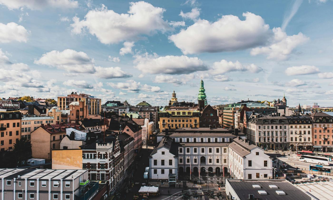 This comundo blog post has a main imagine that shows Stockholm city. There is a blue sky with white fluffy clouds above, and the city is bathed in sunlight.