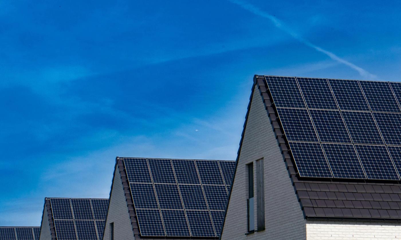 This comundo blog post about ESG and carbon accounting in 2026 has a main image that shows a row of what looks like residential buildings' rooftops, each with solar panels installed. It's a very symmetrical photo, and the sky behind the row of rooftops is clear and blue.