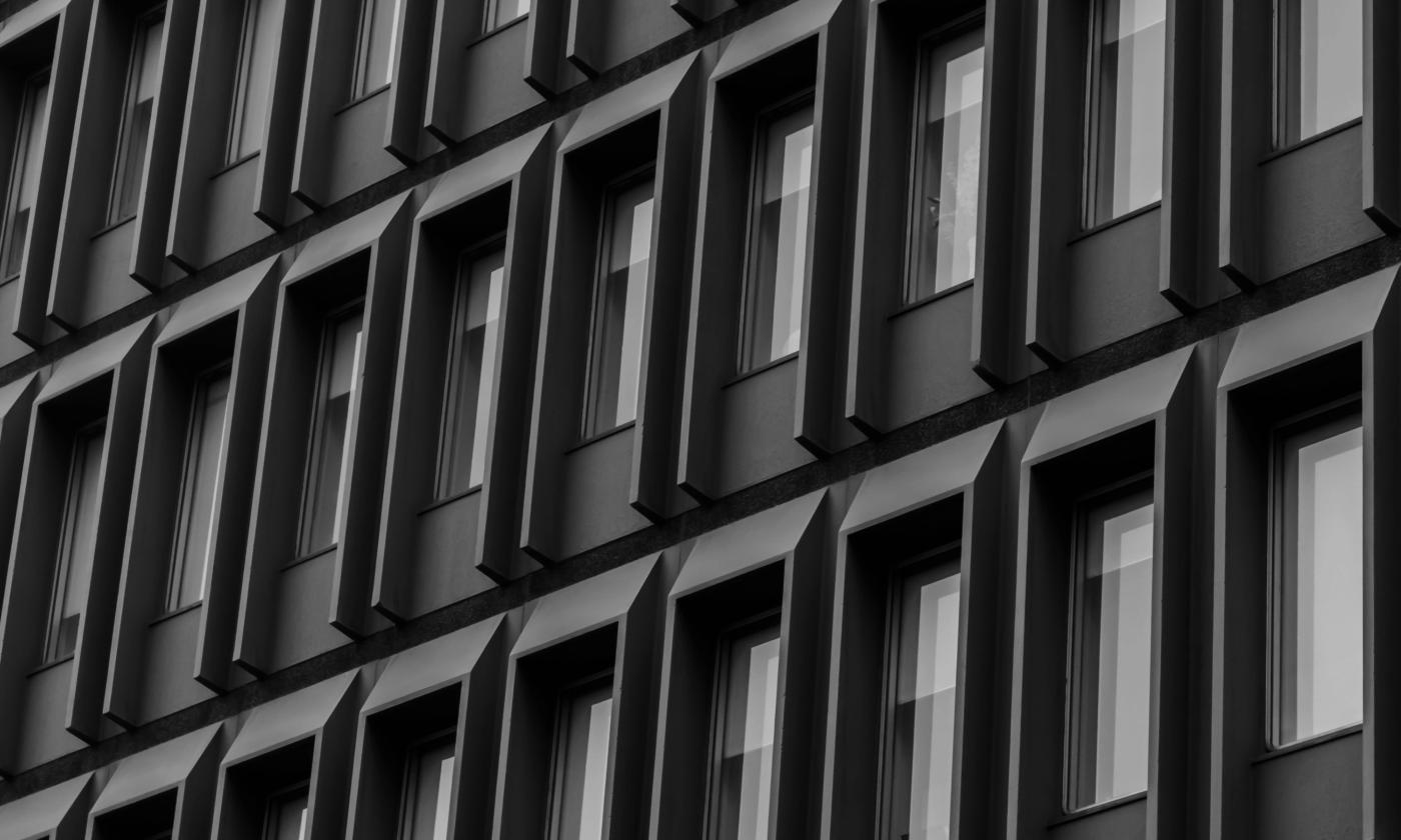 The main image for this comundo blog post about measuring tenant energy data is an extreme close-up of a block of flats or office block. All we can see are windows. The facade is a dark grey-brown colour