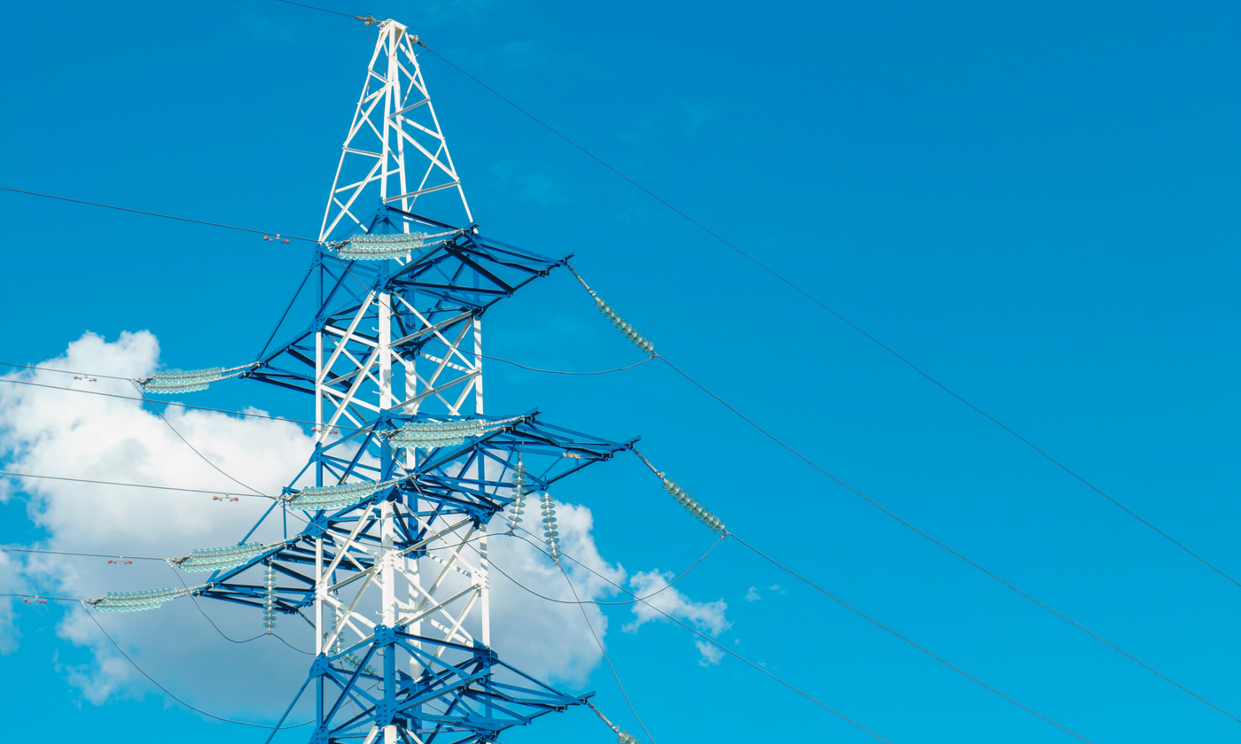 A photo showing the top half of an electricity pylon against a blue sky