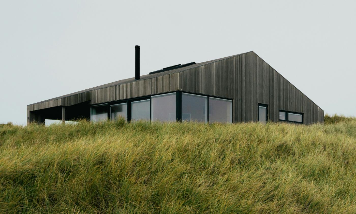 This comundo blog post about CSRD has a header image of a moody sky, a wooden house, and a grassy hill in the foreground.