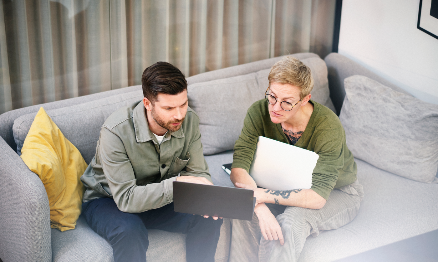 The main image for this comundo blog post about carbon accounting shows a man and a woman sitting on a sofa looking at a computer screen. They're in a relaxed office space and look busy