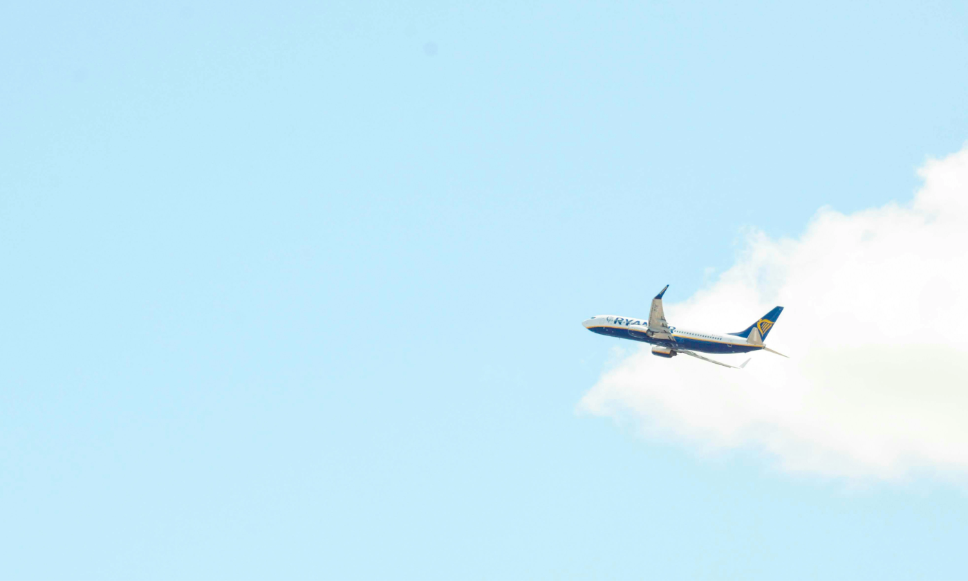 A photo of a Ryanair plane after take-off. The plan is clearly visible against light blue sky and clouds. No buildings or annoyed passengers are in sight