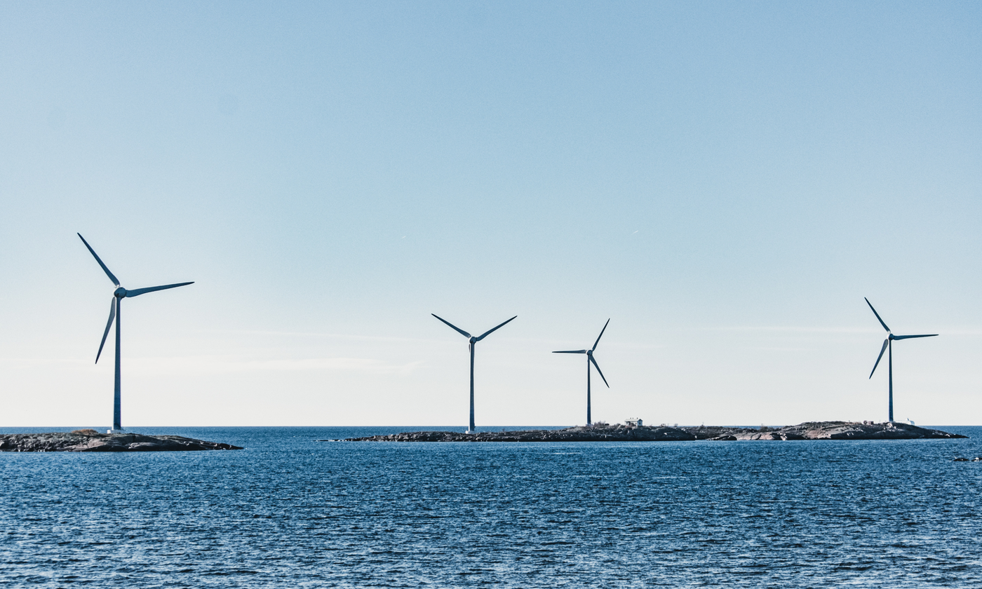 A wide-angle photo of wind turbines on small, rocky islands
