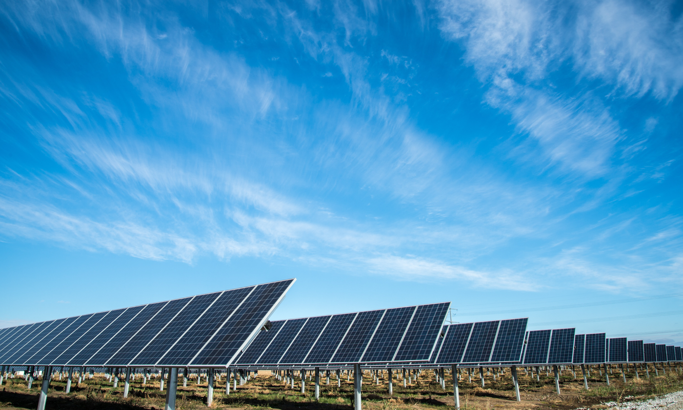 Several rows of solar panels with blue sky behind them