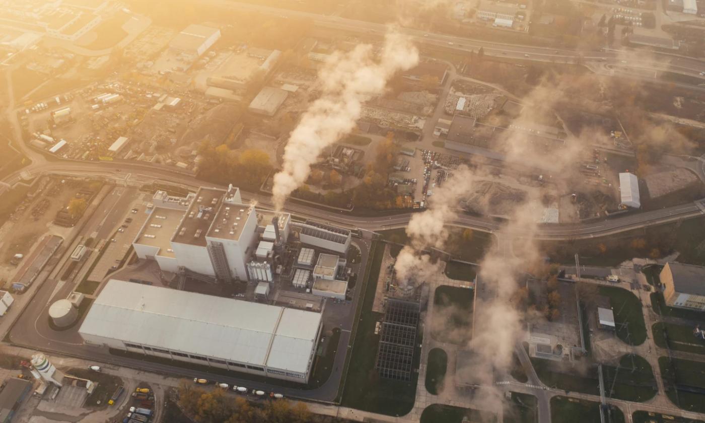 The header image for this comundo blog post about emission factors is an aerial shot of an industrial estate. We can see some smoke stacks, factory buildings, car parks and a road wending its way through it all.