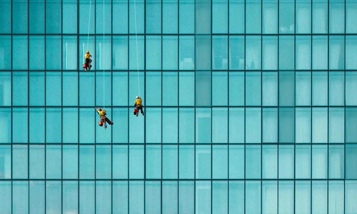 The main image for this comundo blog post about tenant energy data and scope 3 reporting is a close-up photo of an office block. All we can see are windows and three small window cleaners, dangling precariously into the image.