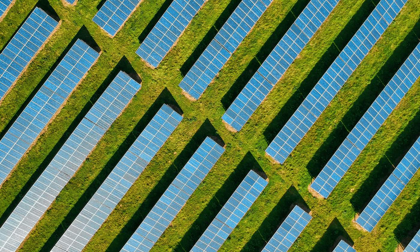 The main image for this comundo blog post about ISO 14001 vs 50001 shows an aerial shot of a number of large solar panels in a green field.
