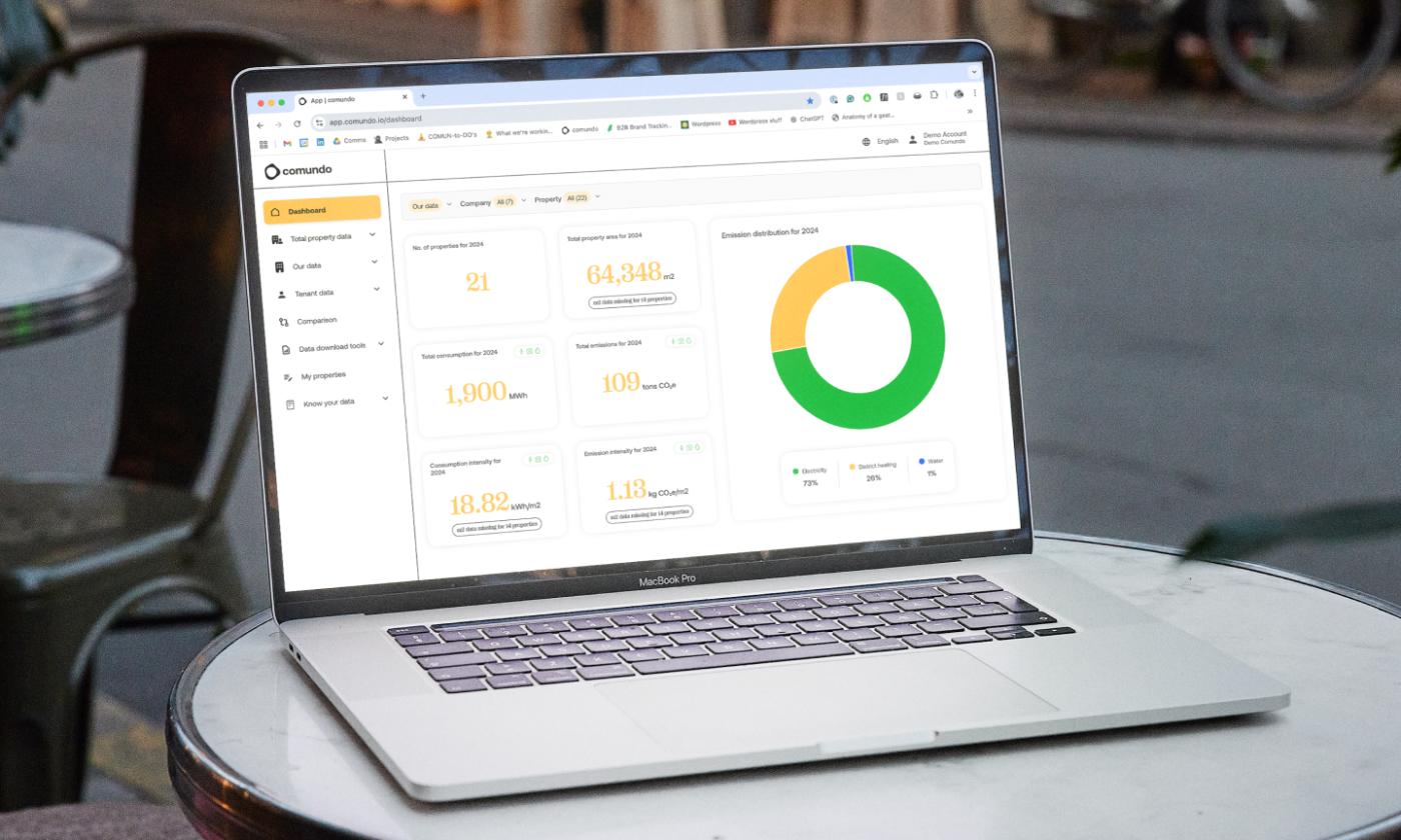 The main image for this comundo blog post about gathering data and streamlining emission data with comundo shows a laptop on a table. On the laptop, we can see comundo's platform which shows a company's energy data displayed, quite beautifully