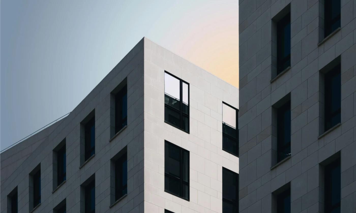 This comundo blog post about GRESB building certification features a main image of the corner of a building. The building is white and the sky behind a hazy blue and orange. Like a sunset