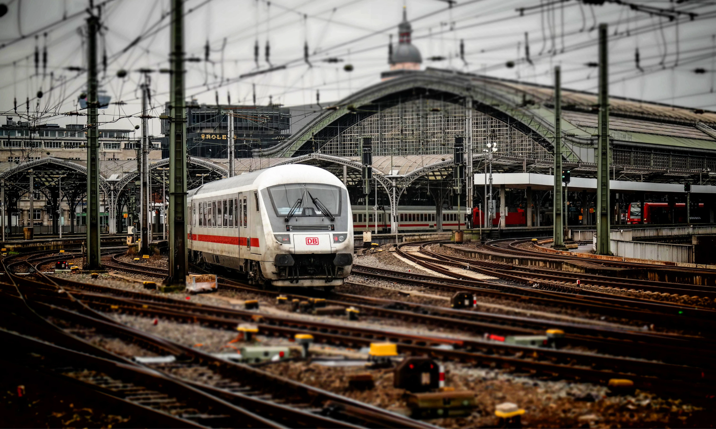 A train pulling out of a main terminal in Germany. There are a lot of railway tracks visible and overhead power lines.