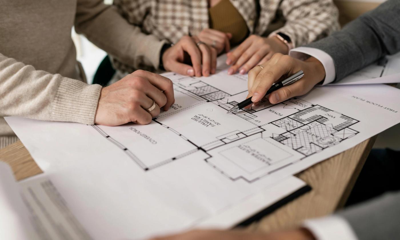 This comundo blog post about EPCs has header image that shows three people working over technical drawings of a house. We can only see their hands, and it looks like they are discussing the plans.