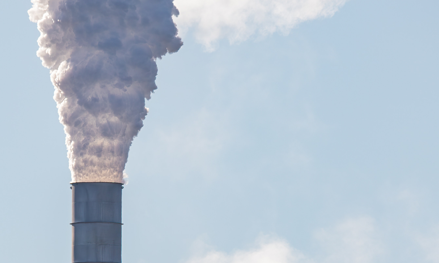 The main image for this comundo blog post about the future of carbon accounting shows the top of one smoke stack with steam billowing out, directly up and out of the image frame. The sky is light blue and there are a couple of thin clouds