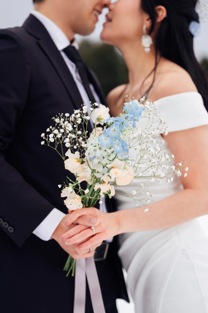 Close-up of pink poppies and eucalyptus leaves adorning a rattan ceremony chair, with a soft, dreamy bokeh background