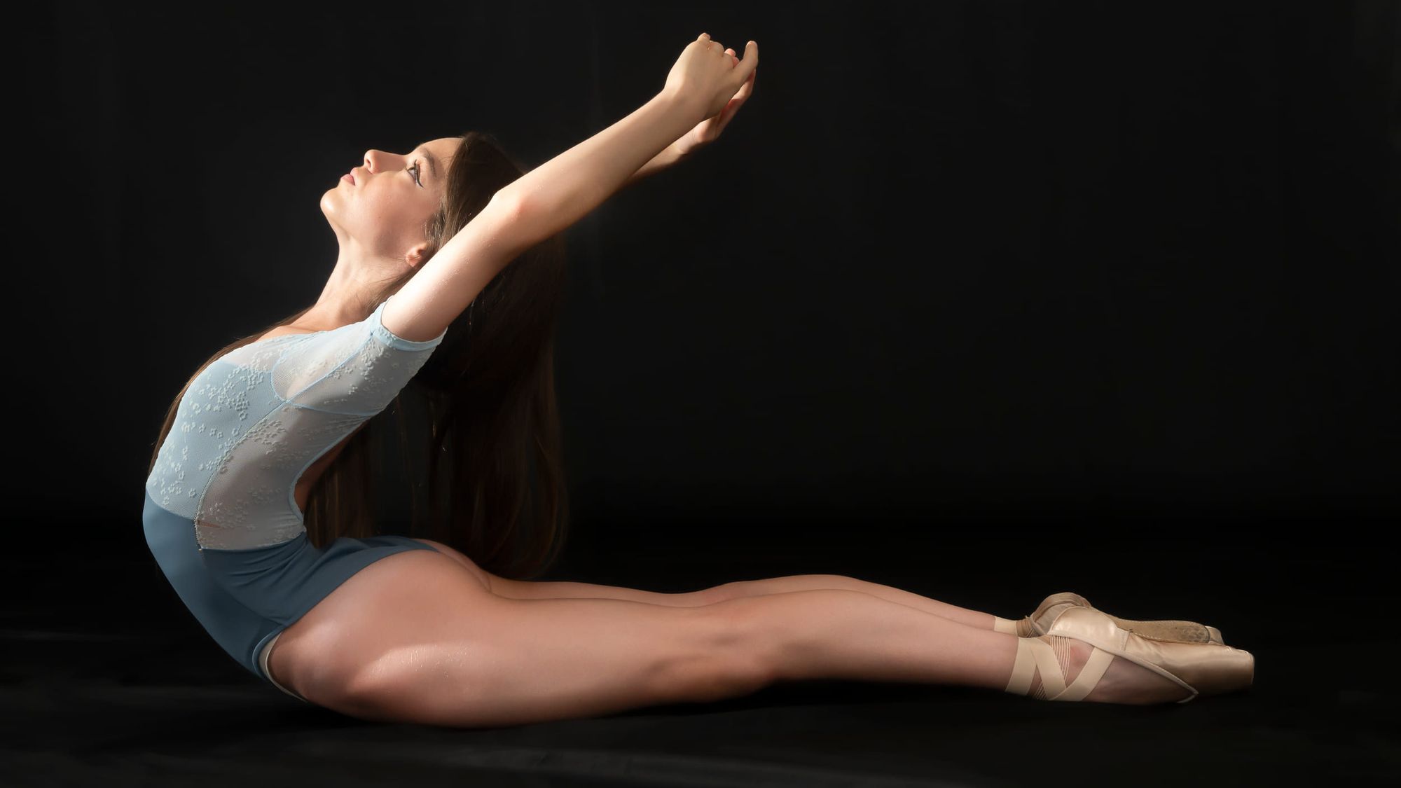 Ballerina distesa a terra che si allunga verso l'alto, in una sala di Art'è Ballet