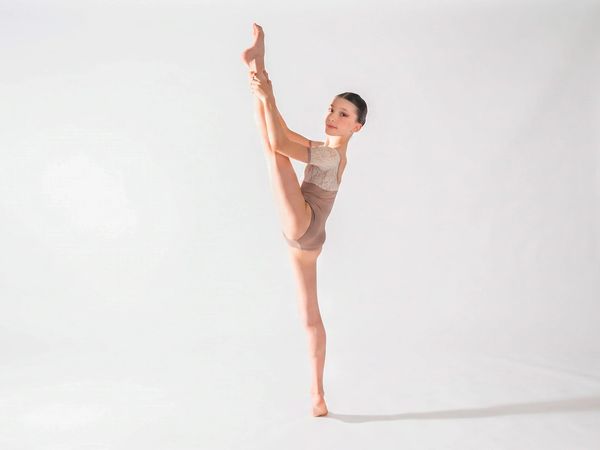 Allieva di danza classica in equilibrio con la gamba tesa verso l'alto