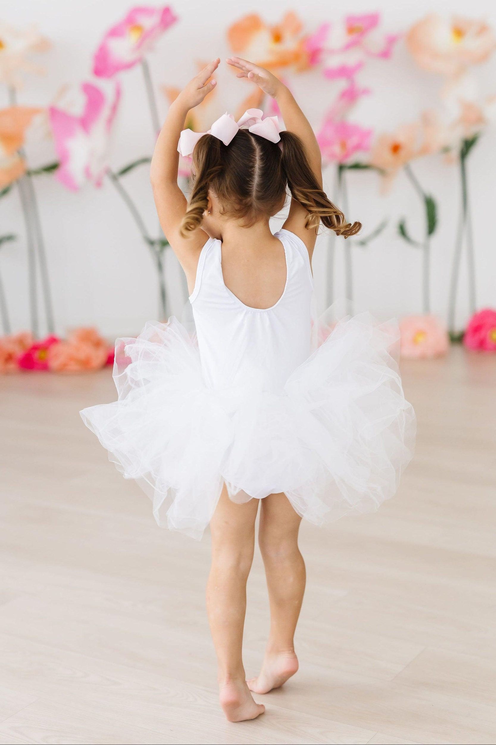 Bambina in tutù bianco con le braccia alzate durante una lezione di propedeutica