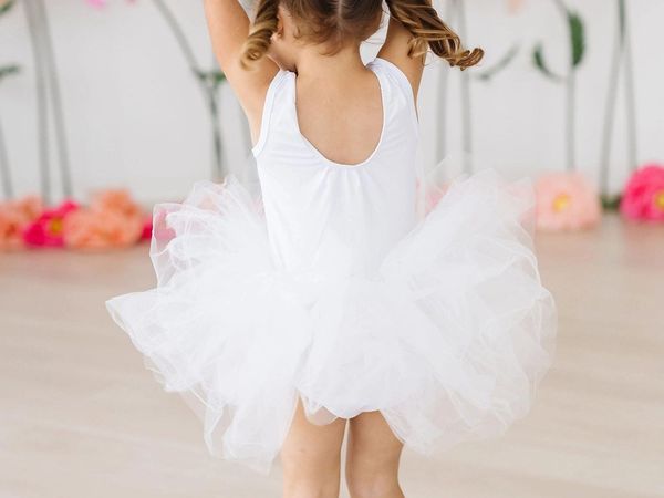 Bambina in tutù bianco con le braccia alzate durante una lezione di propedeutica