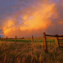A storm cell above a barbed wire fence reflecting bright sunset colours