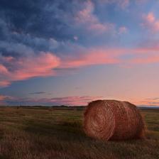 A round bale sitting under an interesting cloud formation at sunset