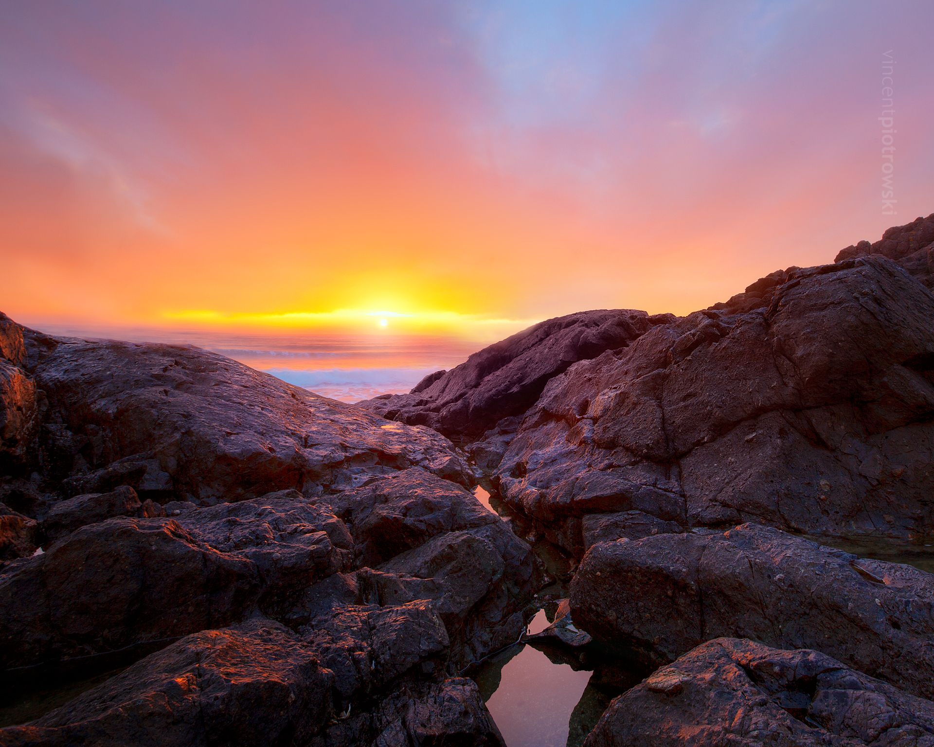 Black rock on the Pacific Ocean with leading lines to the setting sun