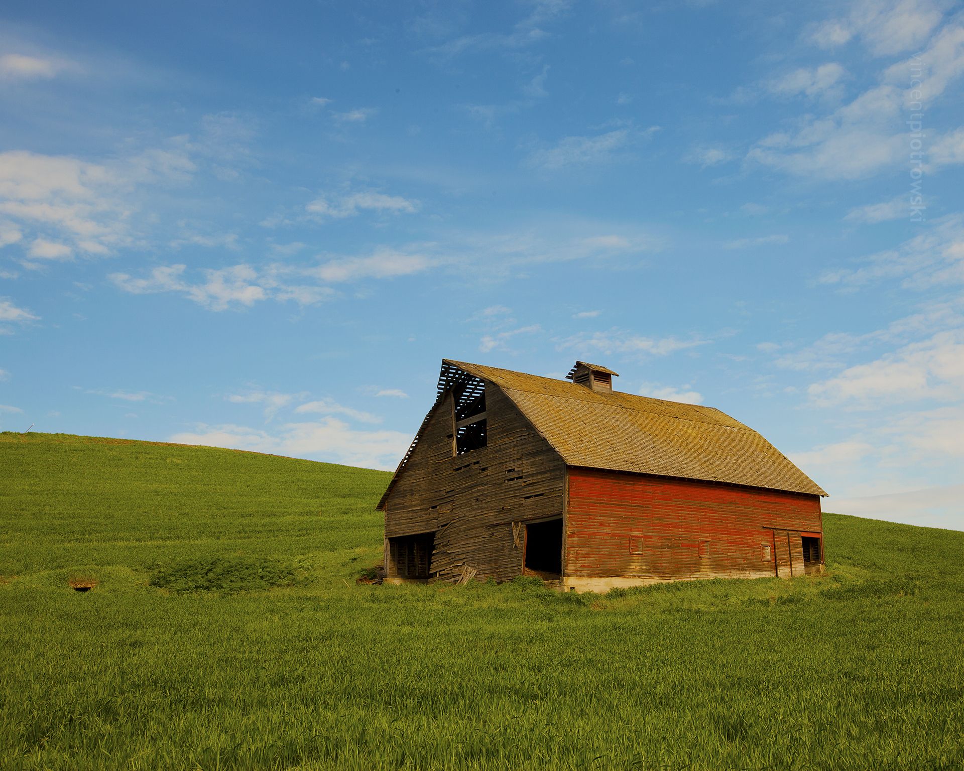A red barn under a blue sky in a green field
