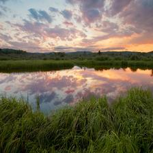 A pond surrounded by green grass in the Alberta Foothills at sunset