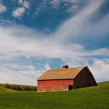A red barn under a blue sky in a green field